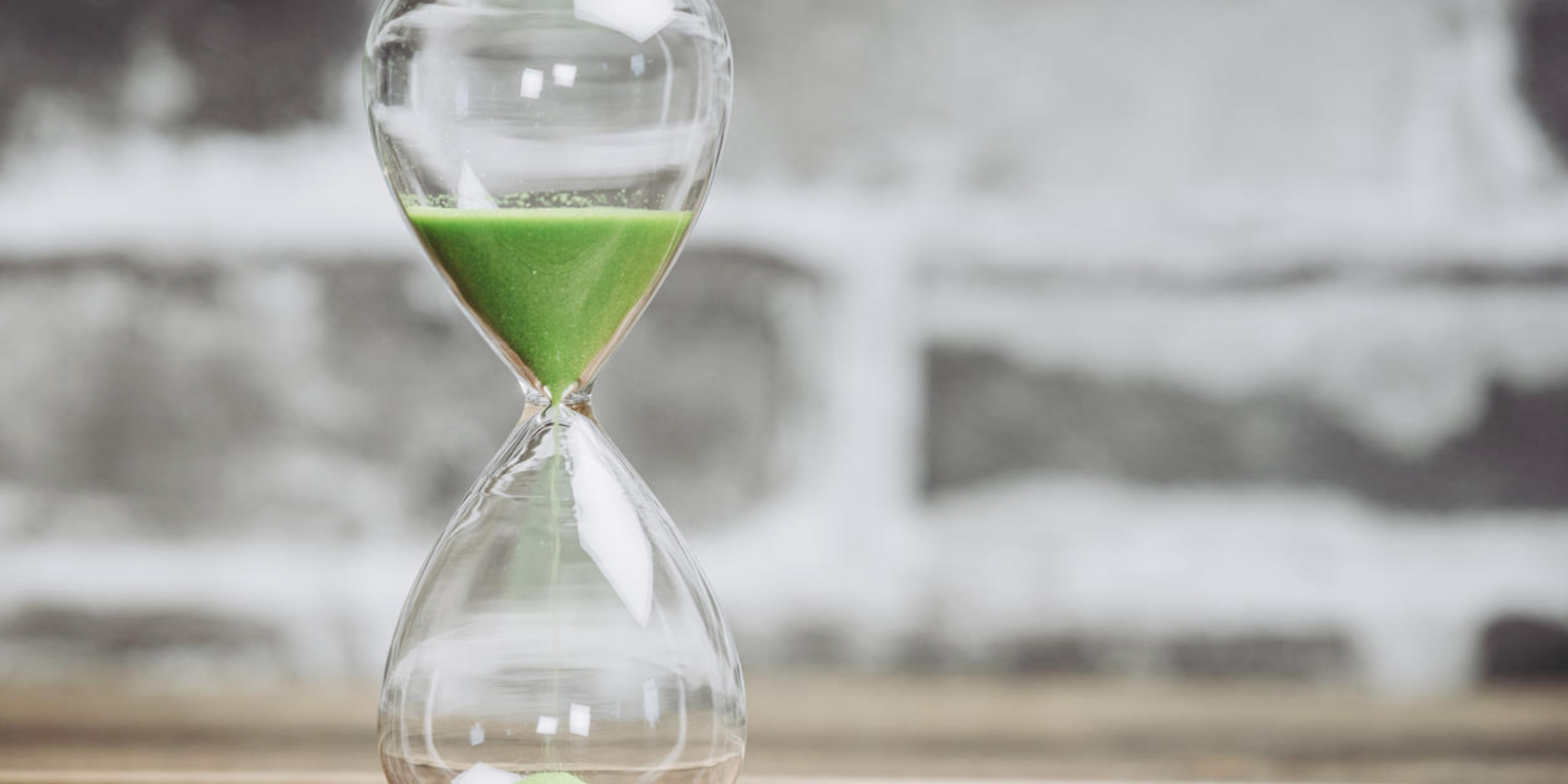 Hourglass with green sand highlighting time decay in options trading and shrinking option value.